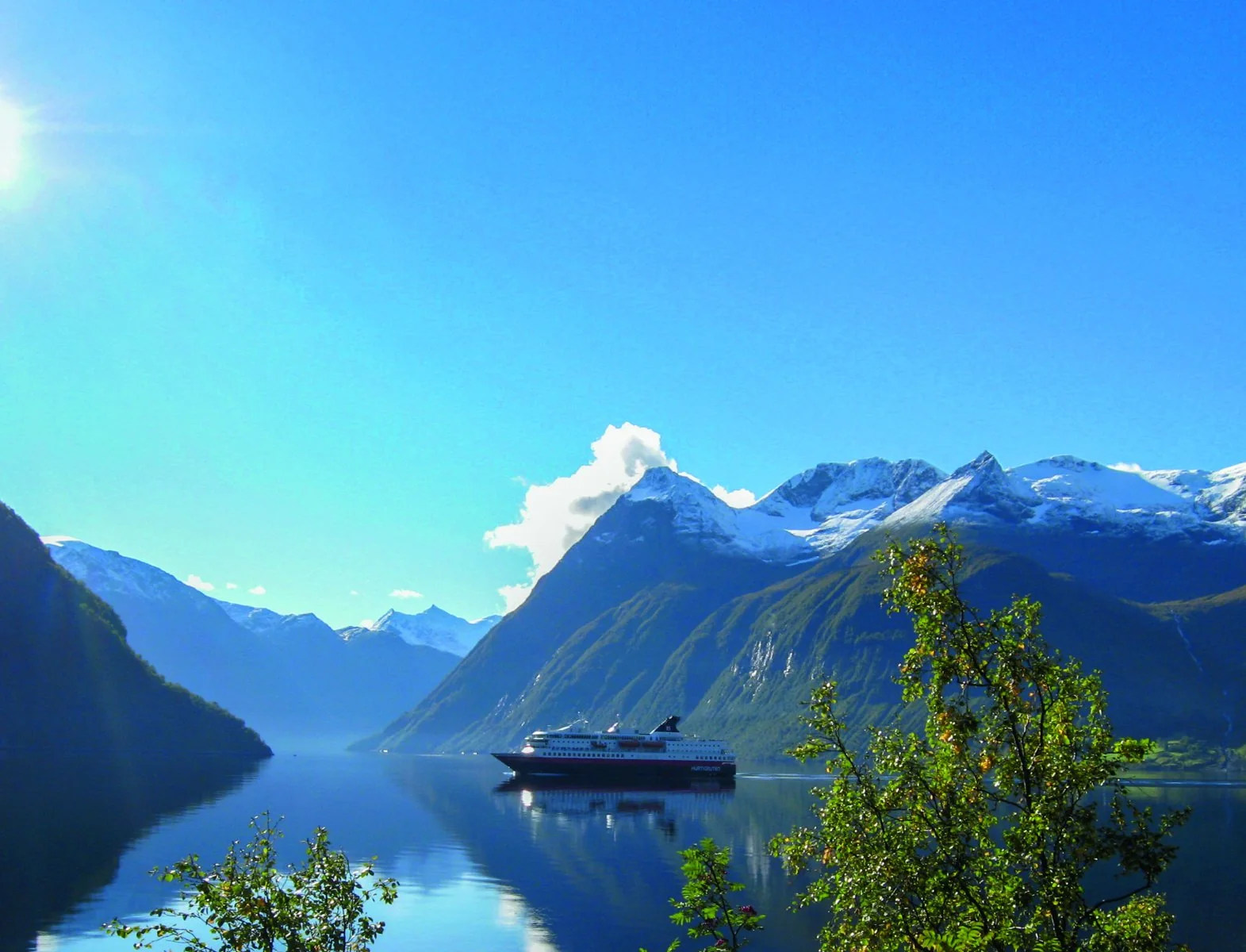 Hurtigrutens fartyg på den norska kusten mellan fjord och fjäll